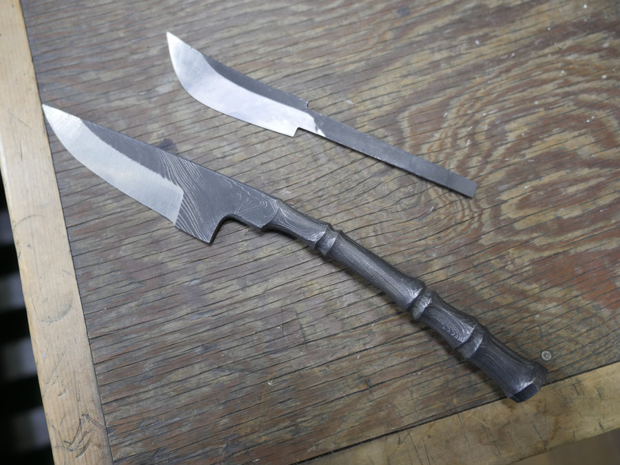 A finished damascus knife with an unfinished blade blank on a workbench, Hinoura workshop, April 2016